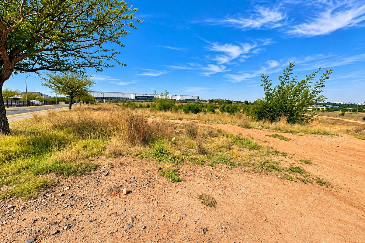 A view of a vacant residential plot featuring natural vegetation and a dirt access path, situated in a developing area.