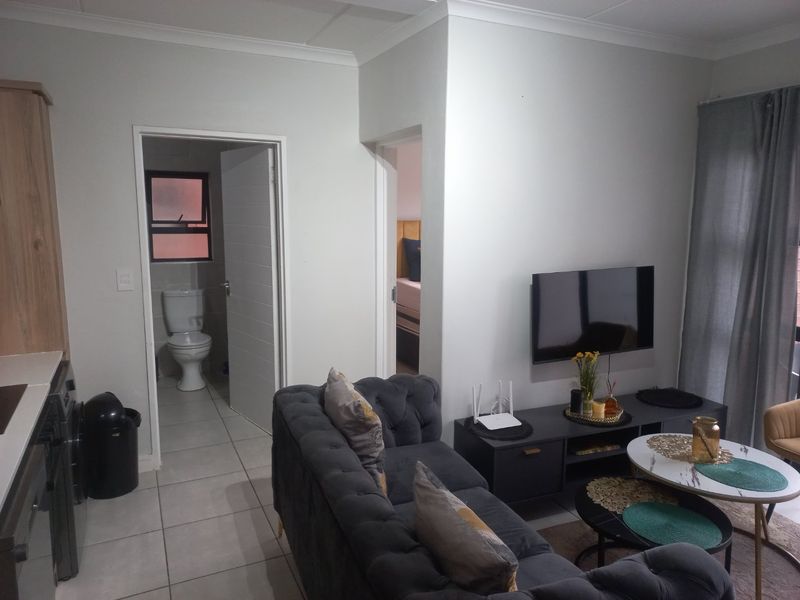 Open-plan living area featuring tiled flooring, neutral walls, and direct access to an adjacent bathroom and bedroom.
