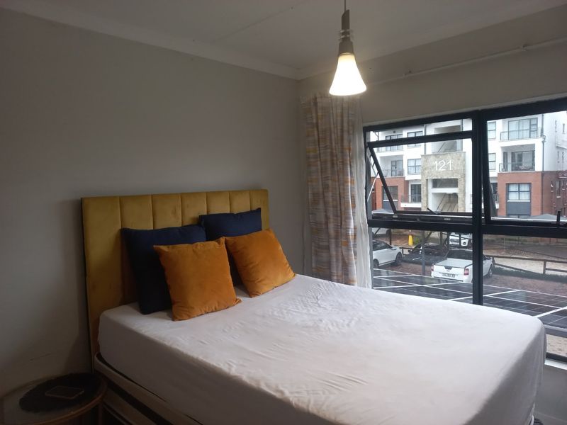 A bedroom featuring a large window with natural light and a modern pendant light fixture.