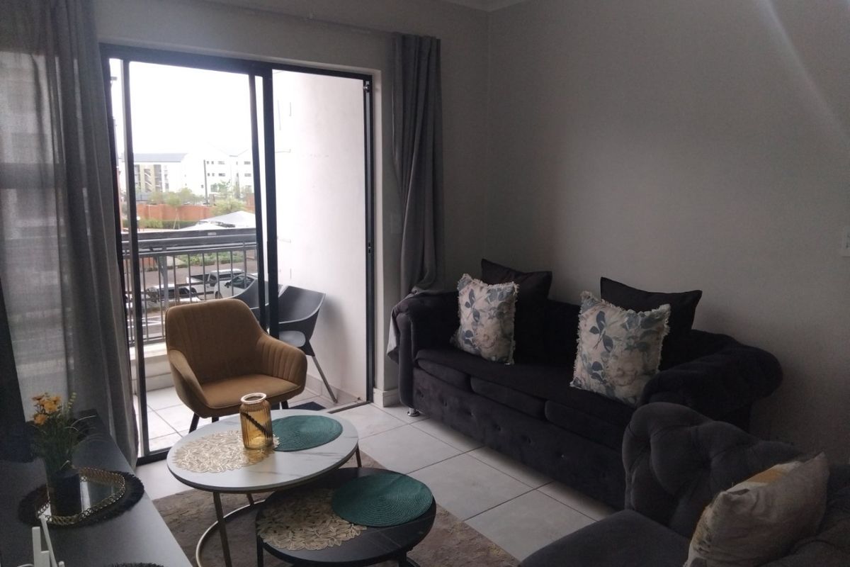 A comfortable living room featuring tiled flooring and a large sliding glass door that provides direct access to an outdoor balcony area.