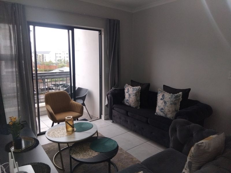 A comfortable living room featuring tiled flooring and a large sliding glass door that provides direct access to an outdoor balcony area.