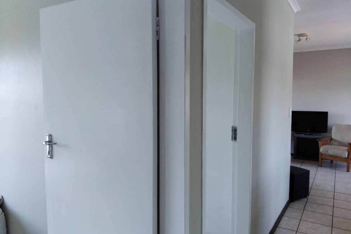 A functional hallway area featuring tiled flooring and access to adjacent rooms through standard internal doors.