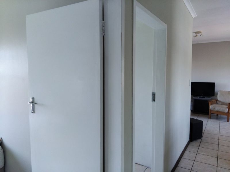 A functional hallway area featuring tiled flooring and access to adjacent rooms through standard internal doors.