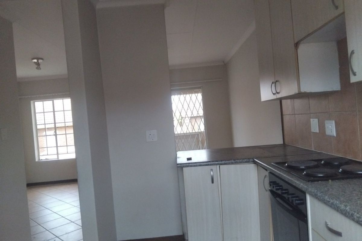 Open plan kitchen and living area featuring tiled floors, built-in cabinetry, and an electric hob, offering a functional and bright living space.