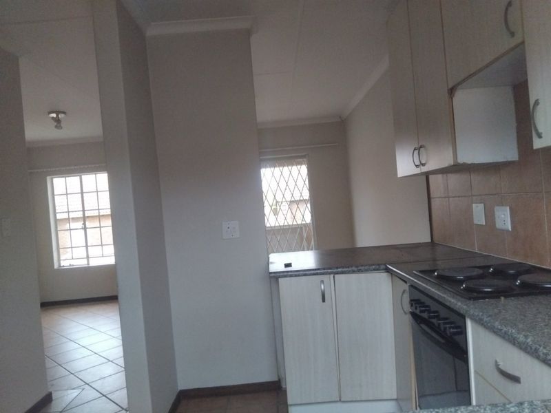 Open plan kitchen and living area featuring tiled floors, built-in cabinetry, and an electric hob, offering a functional and bright living space.
