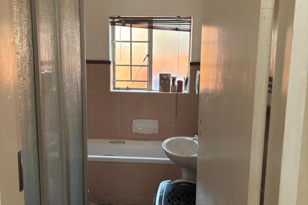 A functional bathroom featuring a shower enclosure, bathtub, and pedestal basin with tiled finishes throughout.