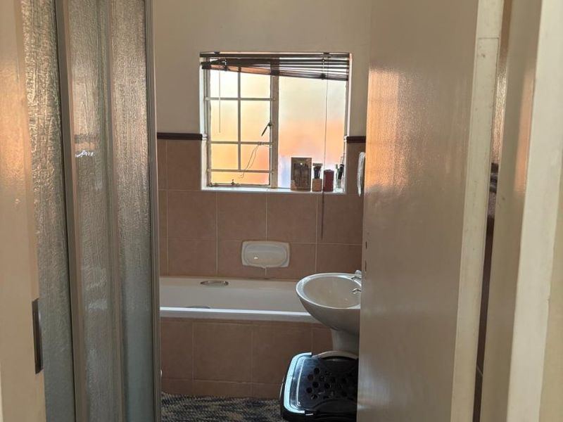 A functional bathroom featuring a shower enclosure, bathtub, and pedestal basin with tiled finishes throughout.