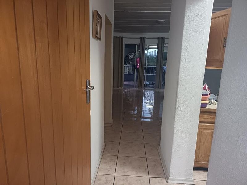 A view through a hallway with tiled flooring, leading towards an open living area with access to a balcony.