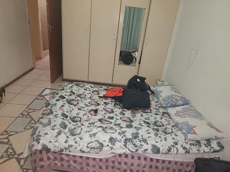 A bedroom featuring built-in wardrobes and tiled flooring, requiring cosmetic updates to improve the overall aesthetic and condition of the space.