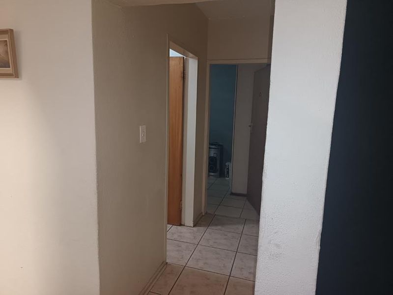A functional hallway featuring tiled flooring and access to multiple internal rooms, showing signs of wear on the wall surfaces.