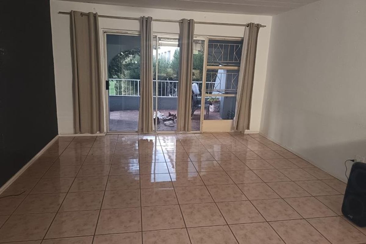 Spacious living area featuring ceramic floor tiles and large sliding glass doors providing direct access to an outdoor balcony.