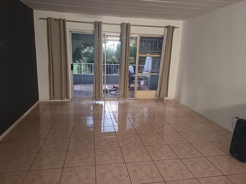 Spacious living area featuring ceramic floor tiles and large sliding glass doors providing direct access to an outdoor balcony.