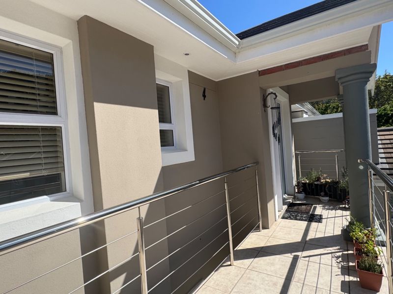 A well-maintained balcony featuring tiled flooring, a modern stainless steel balustrade, and recessed ceiling lighting, providing a clean and functional outdoor space.