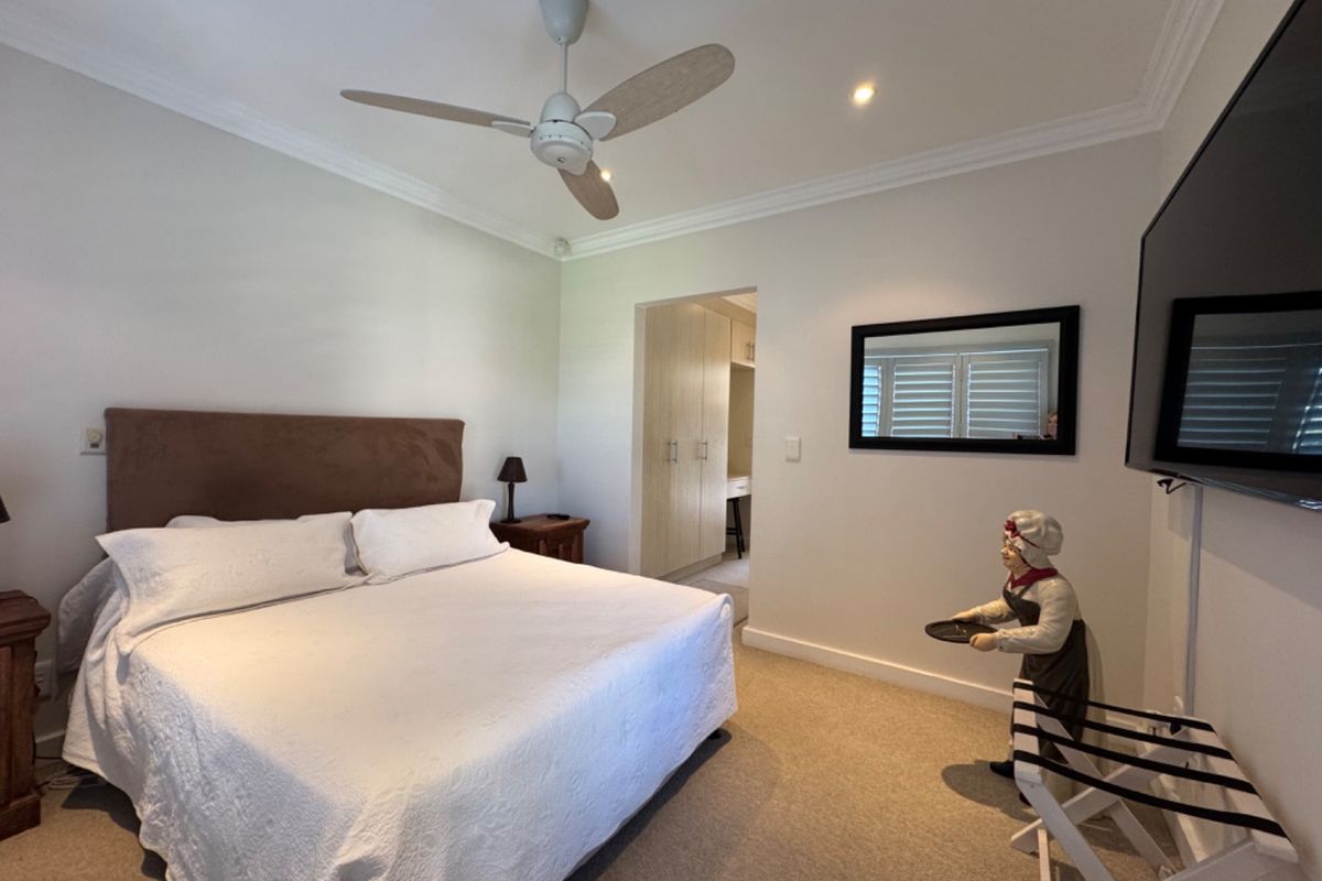 A well-maintained bedroom featuring a ceiling fan, recessed lighting, and built-in cupboards in the adjacent dressing area.