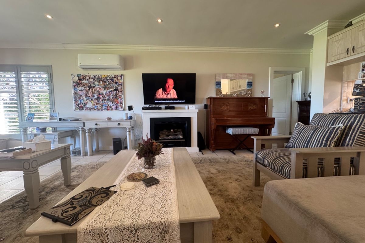 A spacious living room featuring a central fireplace, split-system air conditioning, recessed lighting, and neutral tiled flooring.