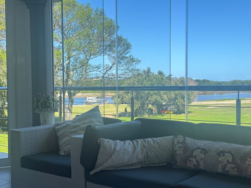 Enclosed balcony featuring a modern stainless steel balustrade and floor-to-ceiling glass panels, offering scenic views of the surrounding landscape and water.