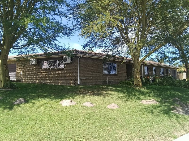 A single-story brick house with a tiled roof, featuring a front lawn, driveway, and garage access.