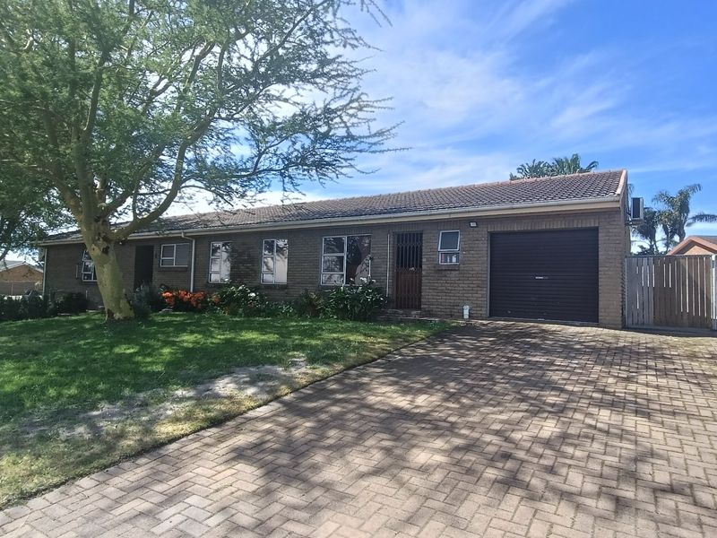 Front view of a single-story brick house featuring a paved driveway, single garage, and established garden area.
