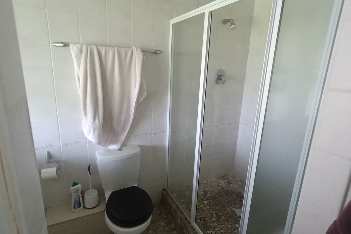 A functional bathroom featuring a shower enclosure with a glass door, a standard toilet, and tiled wall finishes.