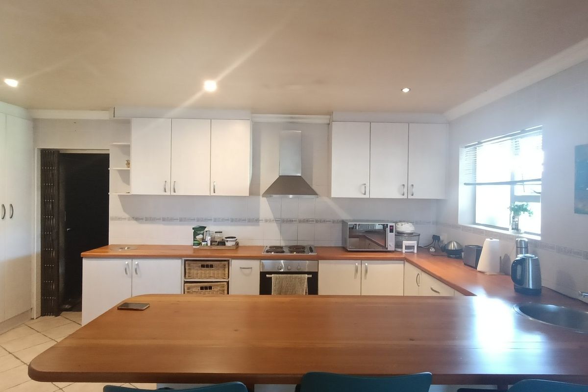 A functional kitchen featuring white cabinetry, wooden countertops, a built-in oven with gas hob, and a stainless steel extractor fan.