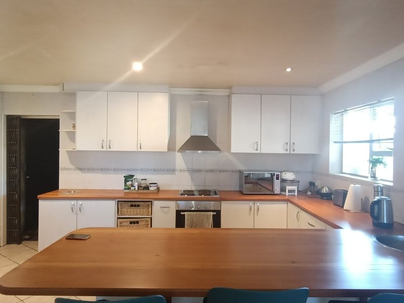 A functional kitchen featuring white cabinetry, wooden countertops, a built-in oven with gas hob, and a stainless steel extractor fan.