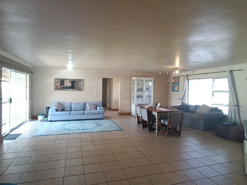 Spacious open-plan living and dining area featuring large format floor tiles, sliding door access to the exterior, and a wall-mounted air conditioning unit.
