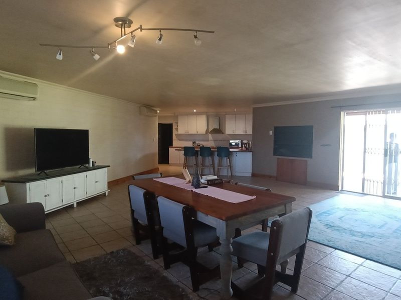 Spacious open-plan living, dining, and kitchen area featuring tiled flooring, split-system air conditioning, and direct access to the outdoor patio through sliding glass doors.