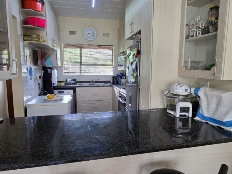 A functional kitchen featuring granite countertops, ample built-in cabinetry, and a breakfast bar, providing a practical layout for daily meal preparation.