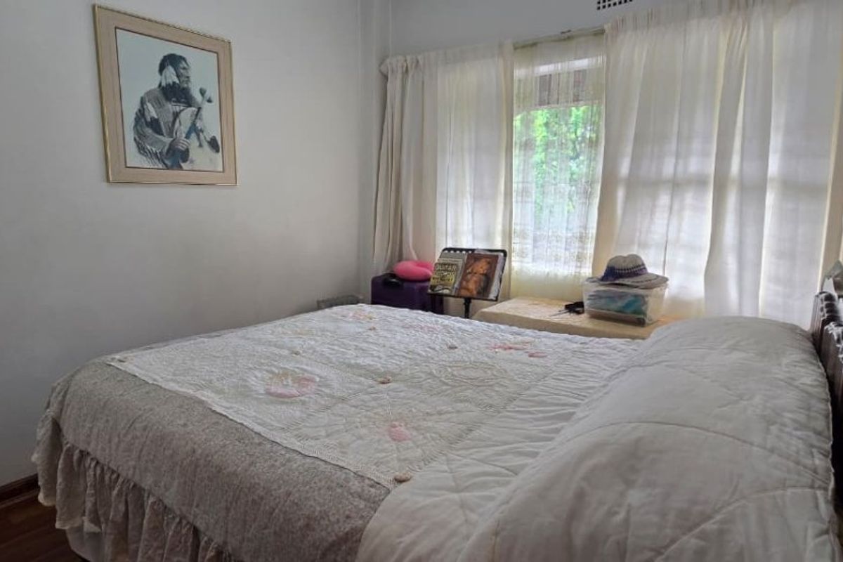 A standard bedroom featuring laminate flooring and window treatments, offering a neutral space ready for personalization.