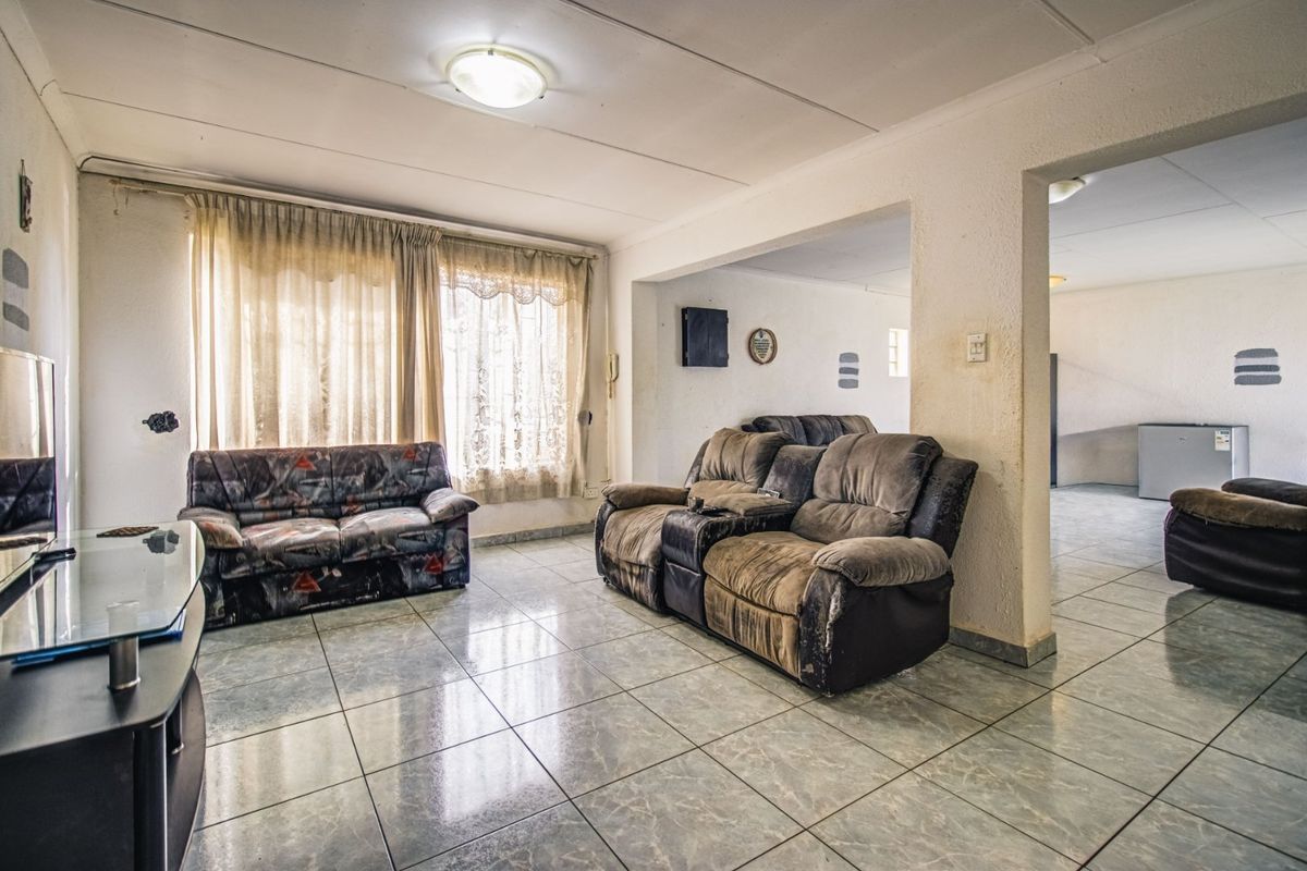 Spacious living area featuring tiled flooring and an open-plan layout, providing a versatile space for relaxation and entertaining.