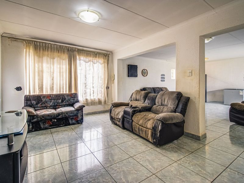 Spacious living area featuring tiled flooring and an open-plan layout, providing a versatile space for relaxation and entertaining.