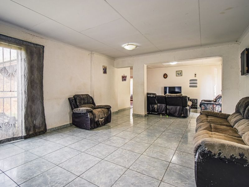 Spacious living area featuring tiled flooring and natural light, offering a blank canvas for renovation and modernization.