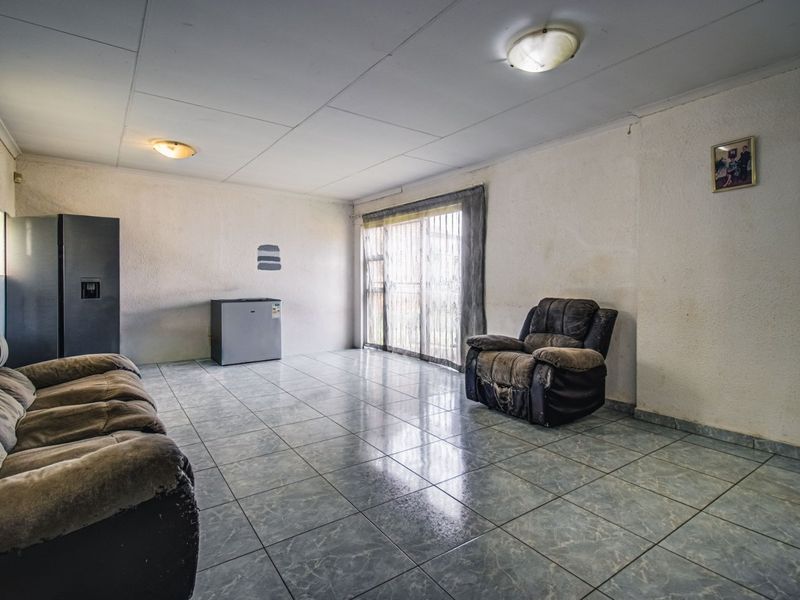A spacious living area featuring tiled flooring, flush mount lighting, and a sliding glass door providing natural light.