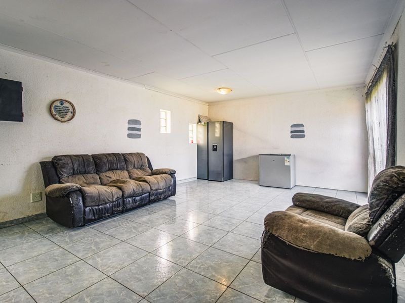 A spacious living area featuring tiled flooring and a neutral wall finish, offering a blank canvas for potential interior updates.