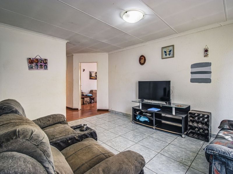 A living room featuring tiled flooring and a textured ceiling, providing a functional space with potential for cosmetic updates and modernization.