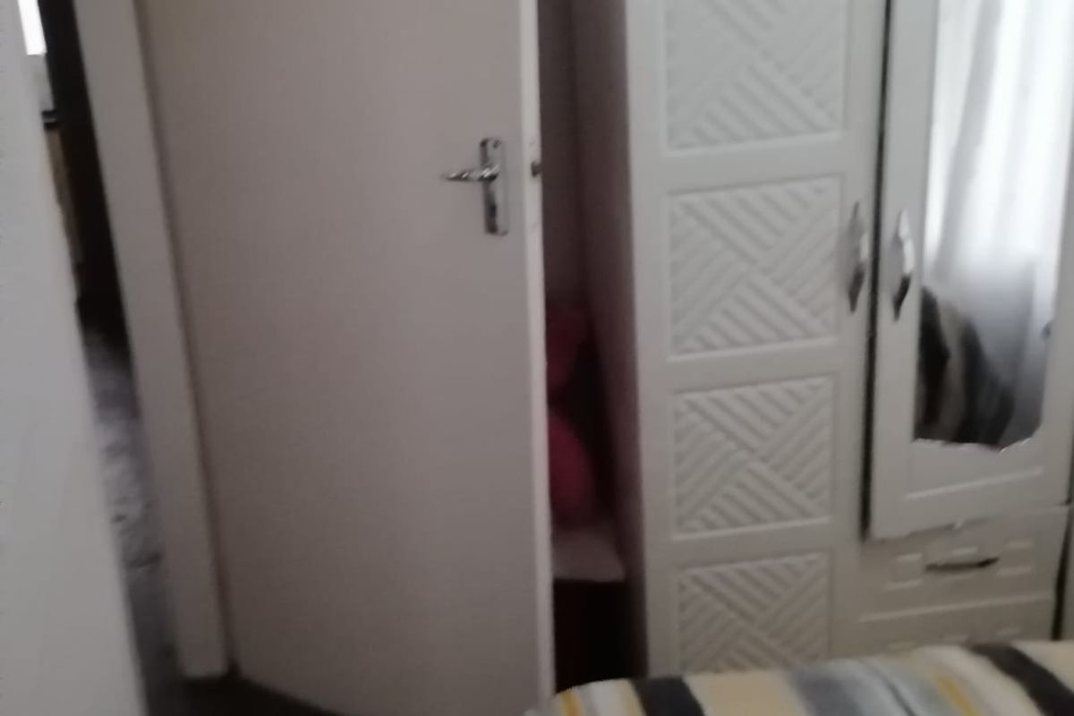 A bedroom interior featuring a built-in wardrobe with a mirrored door panel.