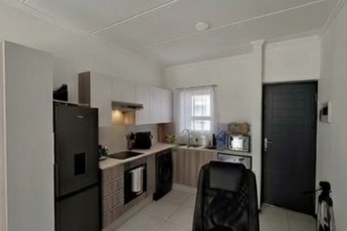 A compact kitchen featuring modern cabinetry, integrated appliances, and tiled flooring, providing a functional and efficient workspace within the apartment.