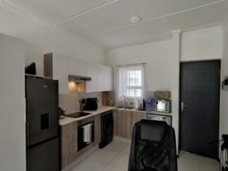 A compact kitchen featuring modern cabinetry, integrated appliances, and tiled flooring, providing a functional and efficient workspace within the apartment.