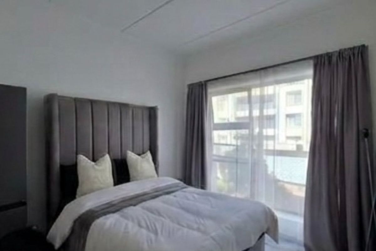 A well-lit bedroom featuring a large sliding glass door with curtain tracks, providing natural light and access to an outdoor area.