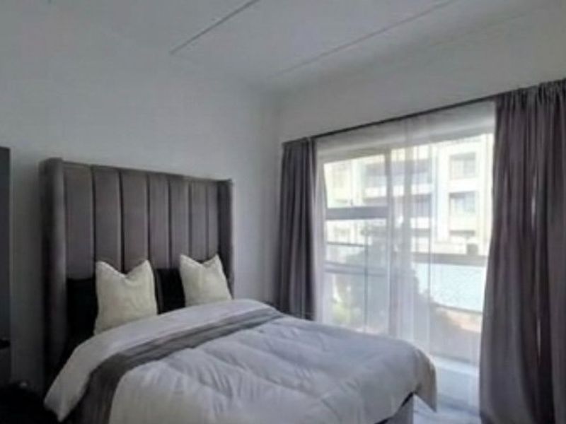 A well-lit bedroom featuring a large sliding glass door with curtain tracks, providing natural light and access to an outdoor area.