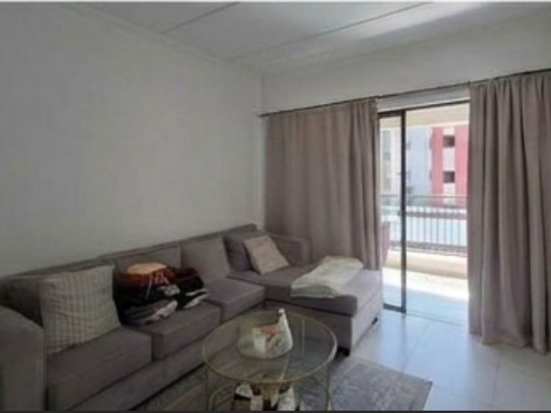 A living room area featuring tiled flooring and a sliding glass door providing access to an outdoor balcony space.