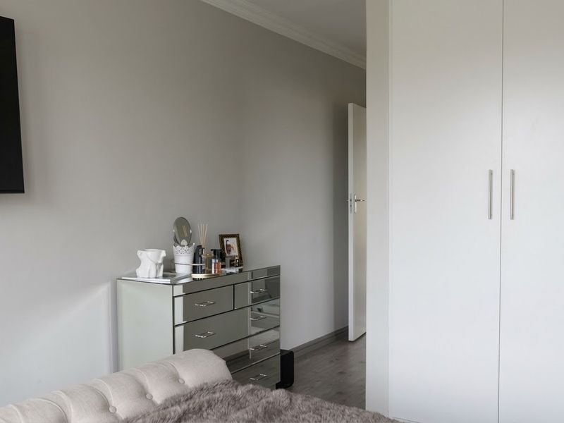 A well-maintained bedroom featuring neutral walls, laminate flooring, and a built-in wardrobe with modern handles.