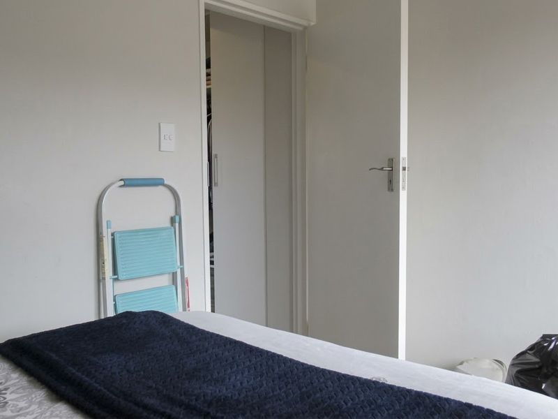 A bedroom featuring a built-in wardrobe and a standard interior door, providing a functional and neutral living space.