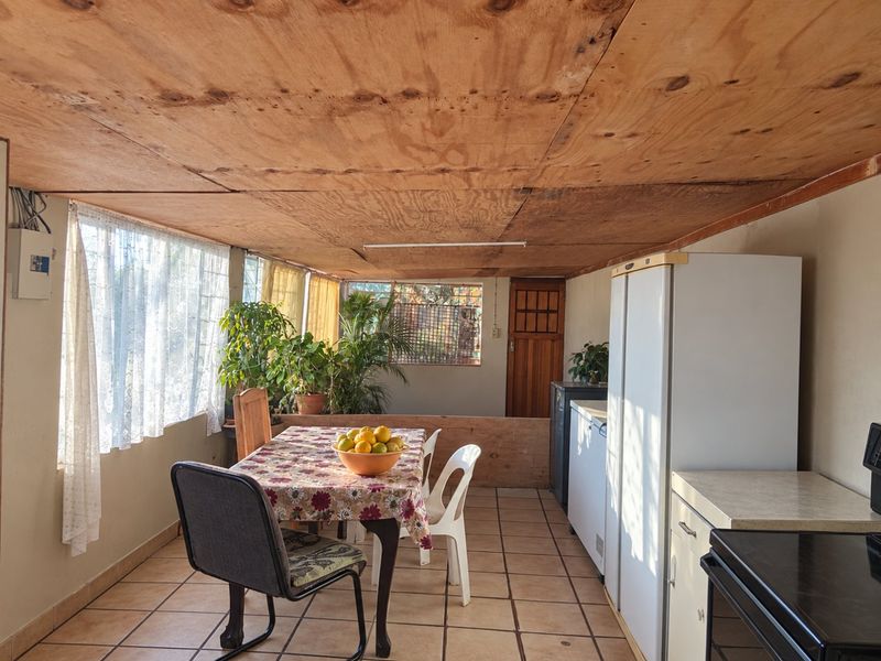 Open plan living and dining area featuring ceramic tiled flooring and a plywood ceiling, offering a functional space with potential for modernization.
