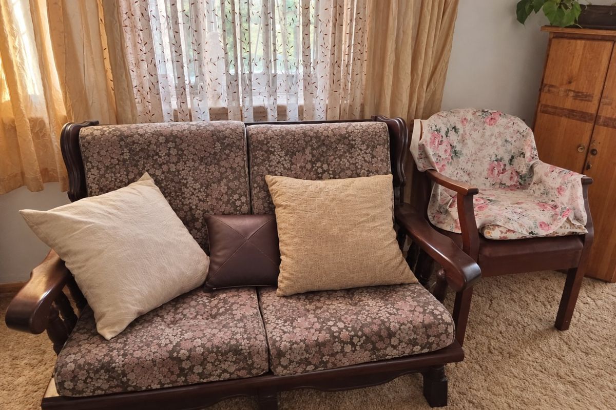 A living room area featuring window treatments and carpeted flooring, providing a functional space for relaxation.