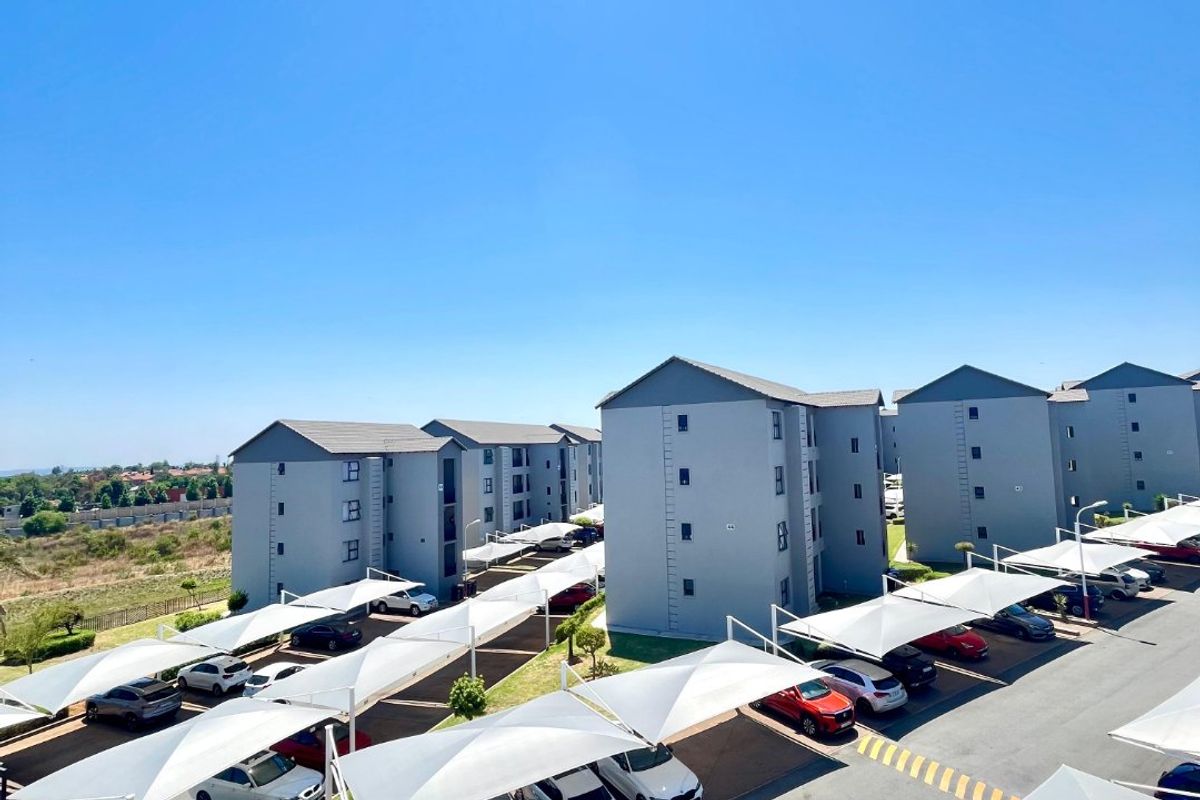 An elevated view of a modern apartment complex featuring multiple residential blocks and designated covered parking bays for residents.