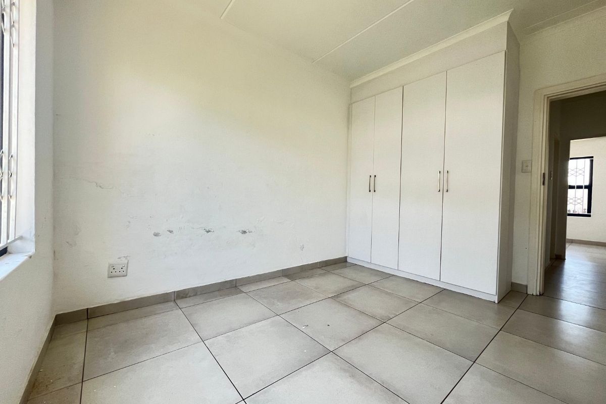 An empty bedroom featuring tiled flooring and built-in cupboards, requiring minor cosmetic attention to the walls.