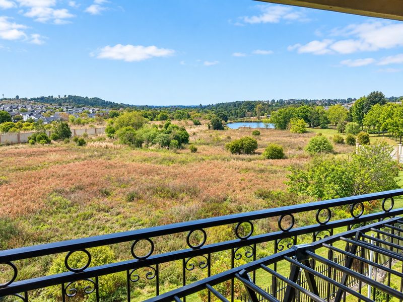 Scenic elevated view overlooking a natural wetland area and distant residential neighborhood, framed by a decorative wrought iron balcony railing.