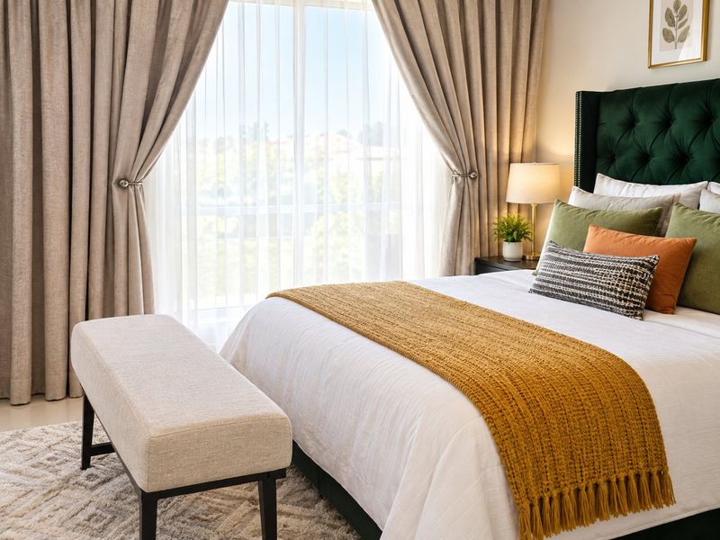 A well-lit bedroom featuring a large window with floor-to-ceiling curtains, providing ample natural light and a pleasant outlook.