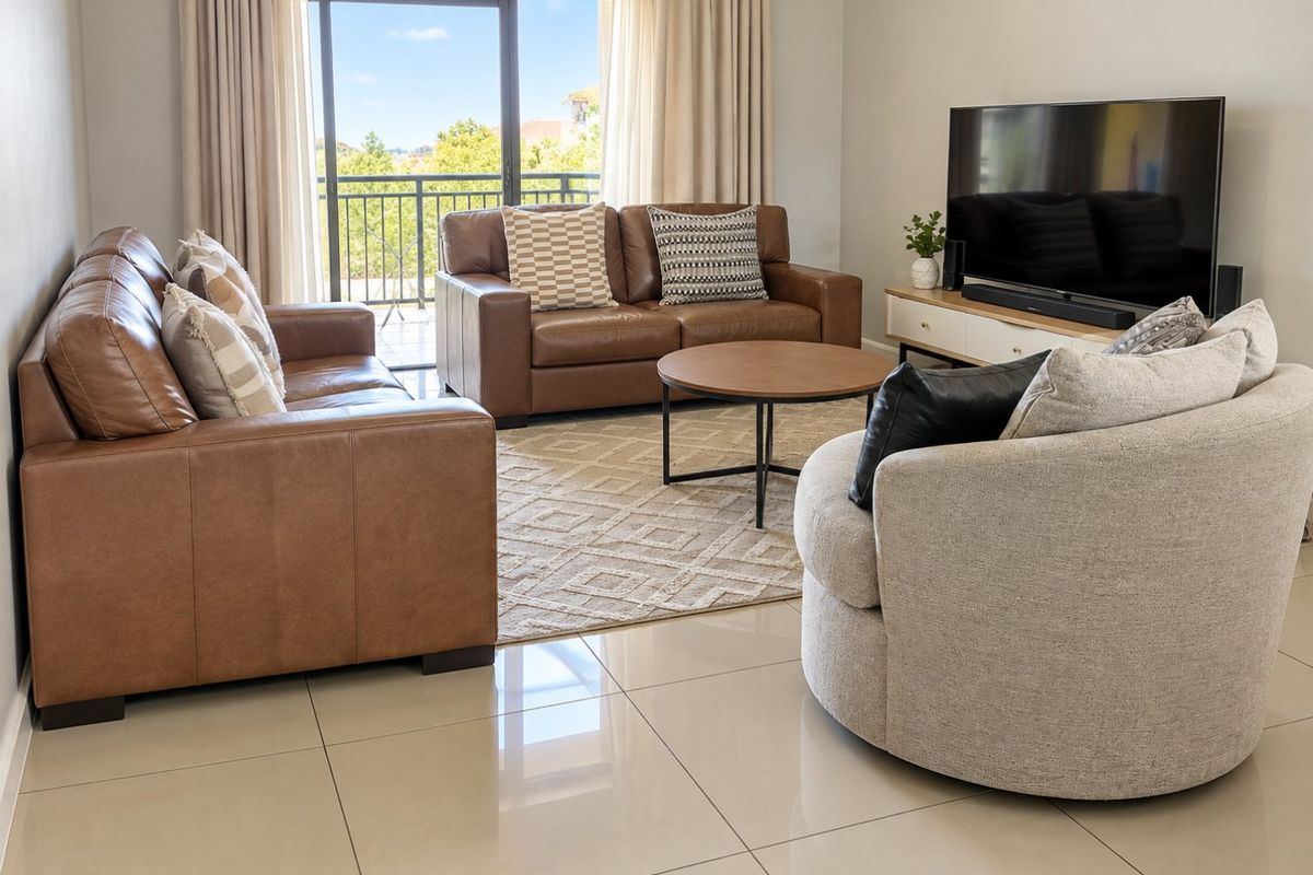 A bright and spacious living room featuring large format tile flooring and a sliding glass door providing direct access to a private balcony.